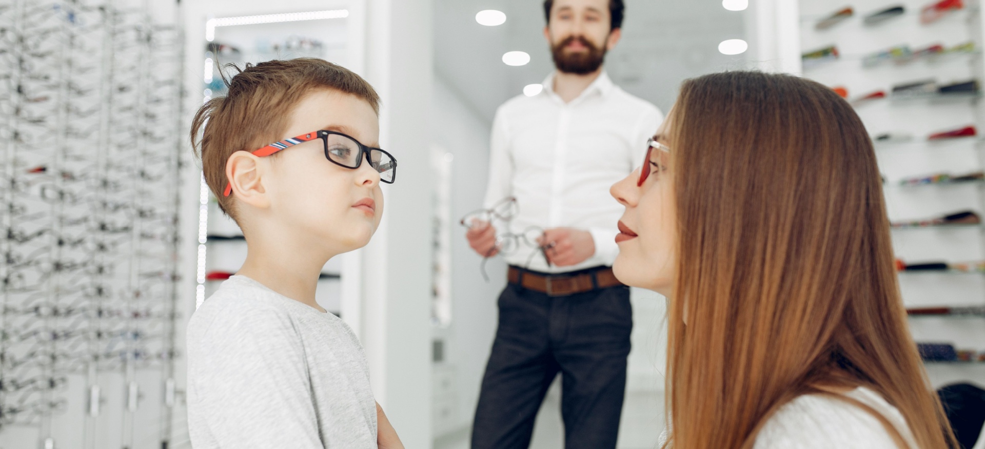 Madre hablando con su hijo pequeño triste en una óptica porque el niño no quiere ponerse gafas.